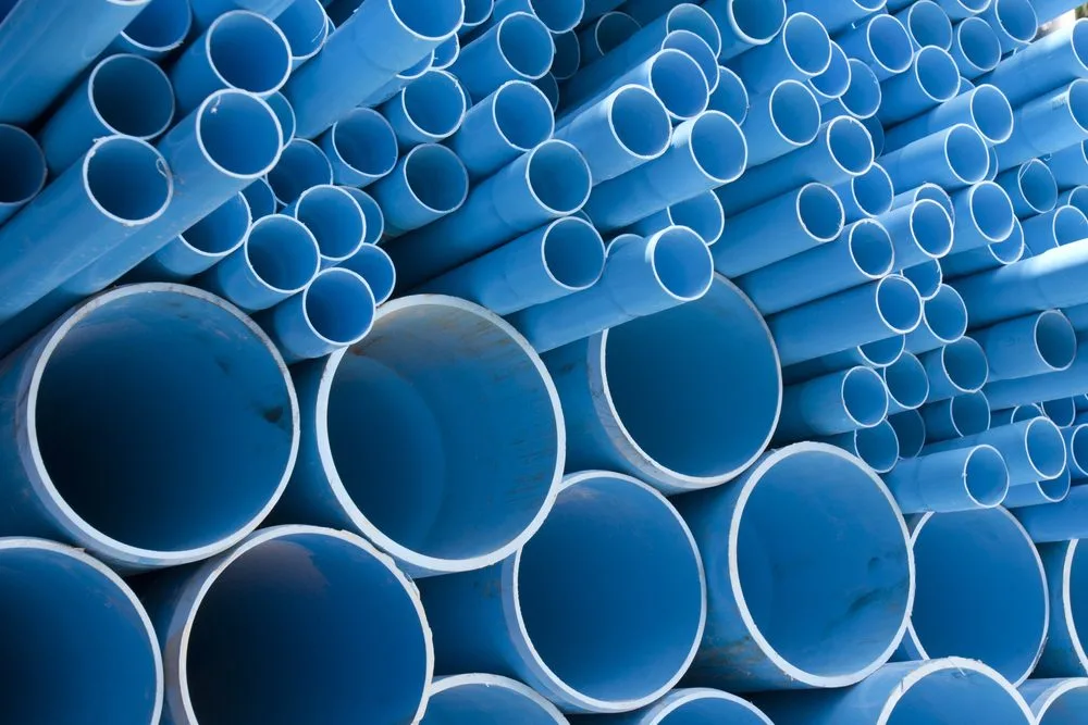 Stacks of blue PVC pipes of various diameters are arranged in a pile in Norfolk, creating a repetitive pattern. The pipes are viewed from the open ends, forming circular shapes.