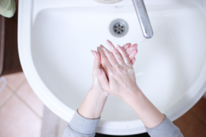 Person washing hands with soap at a white bathroom sink