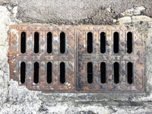 Close-up view of an old, rusted metal storm drain cover
