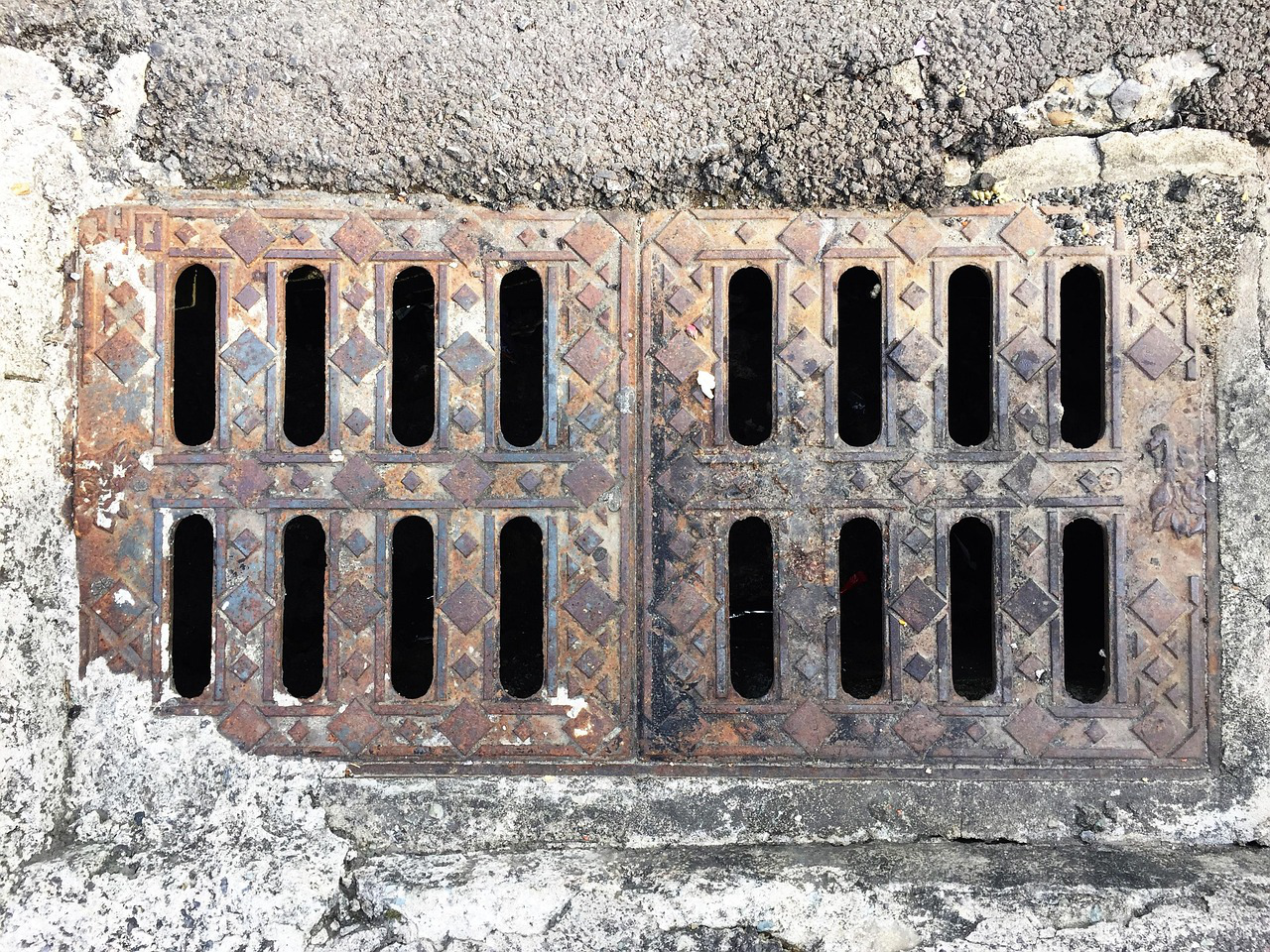 Close-up view of an old, rusted metal storm drain cover