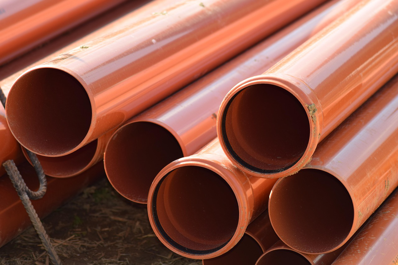 Stack of new orange sewer pipes placed on the ground
