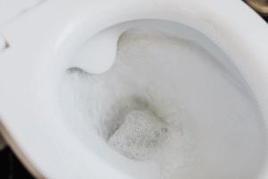 Flushing water in a white ceramic toilet bowl