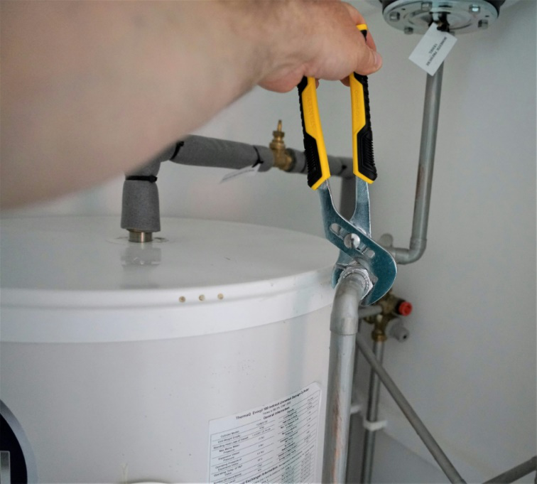 Plumber using a wrench to repair a pipe after leak detection to prevent costly water damage