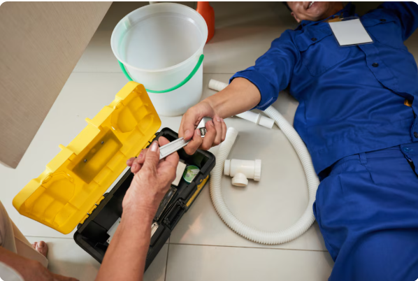 Homeowner handing tools to a plumber during sewer line repair in Brockton, MA
