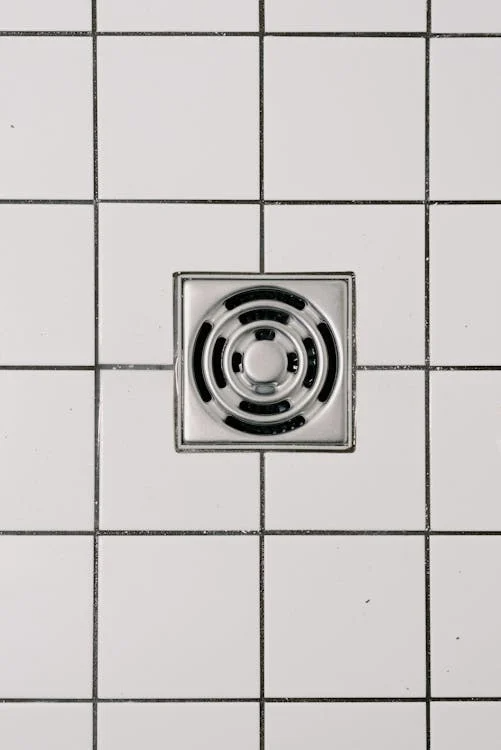 Close-up of a shower drain in a bathroom, highlighting potential plumbing issues