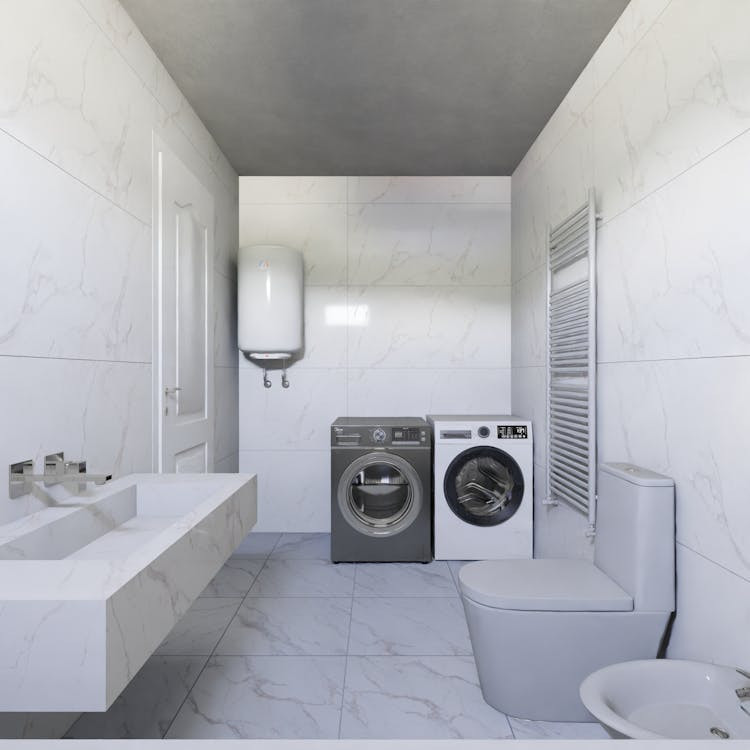 Modern white bathroom with a floating sink, water heater, washing machine, dryer, toilet, and bidet—all set against marble-patterned tile walls and floor. A towel radiator is mounted on the right wall; perfect for homes in Suffolk County or Middlesex.