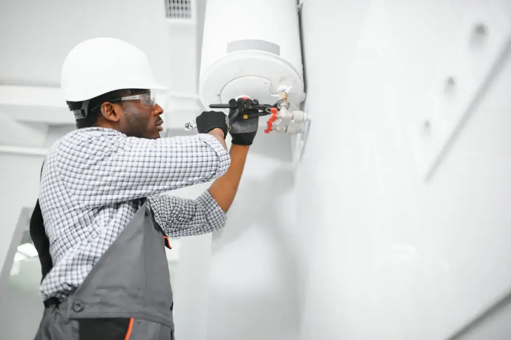 A man in a hard hat working on a gas tank.